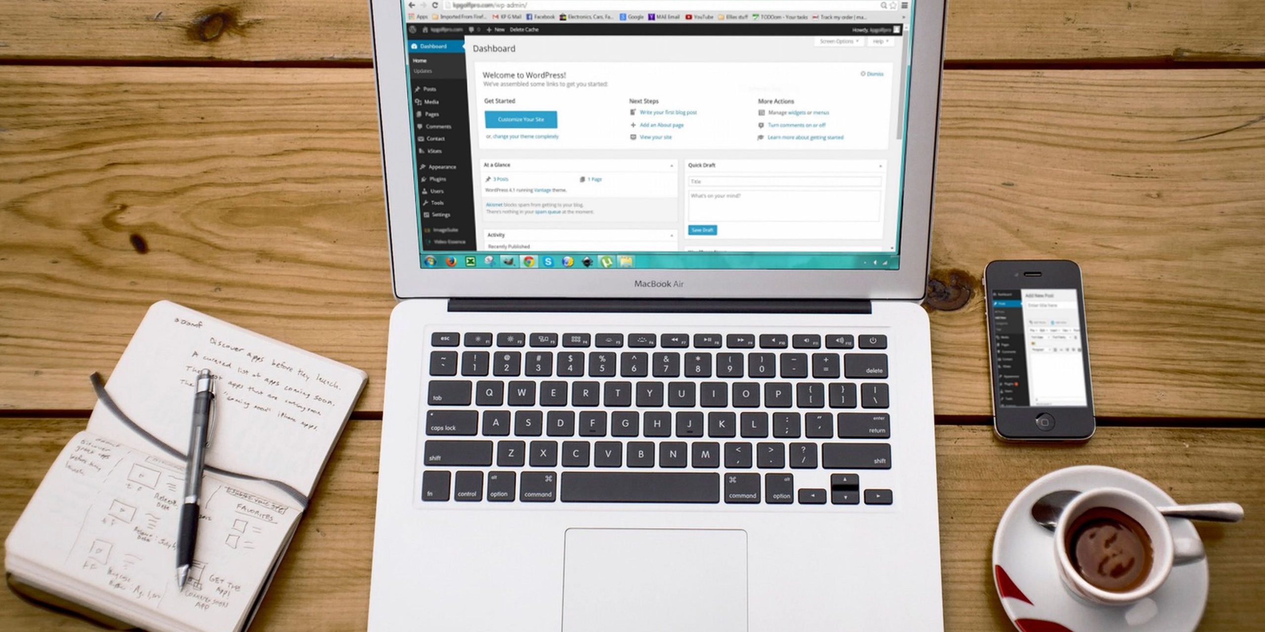 como-saber-blog-traz-clientes-wordpress Portátil com o painel do WordPress aberto, junto a um caderno, um telemóvel e uma chávena de café.