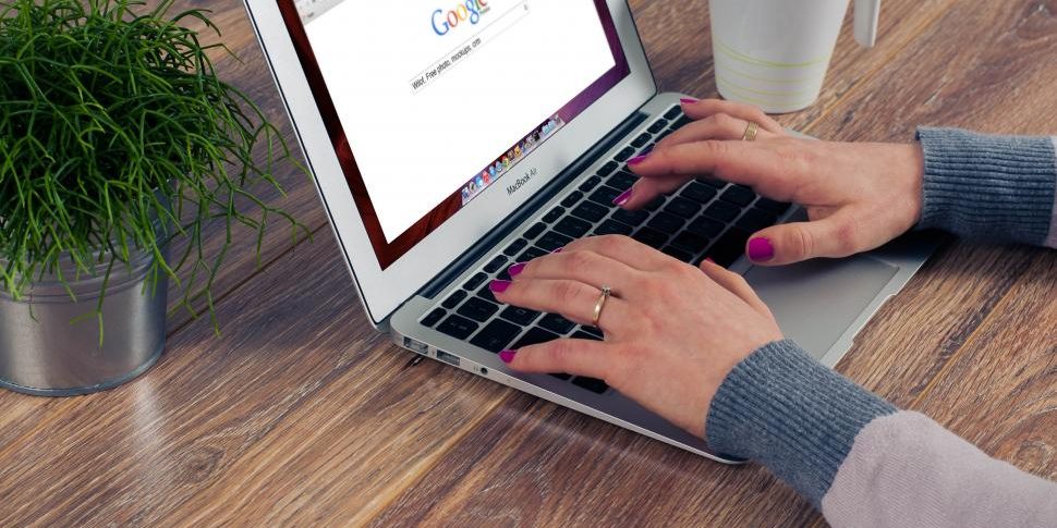 Links nas respostas de IA do Google: o que muda para as empresas Mãos de uma mulher a pesquisar no Google num computador portátil.